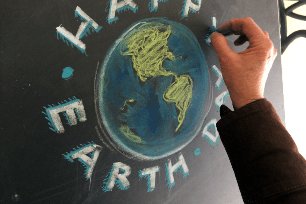 Community member draws Earth Day sign on a chalk board to advocate for issues that matter to them.