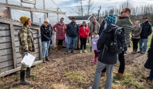 A group of people listen to a farm tour leader