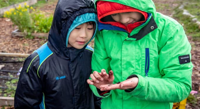 Two children take a close look at a worm.