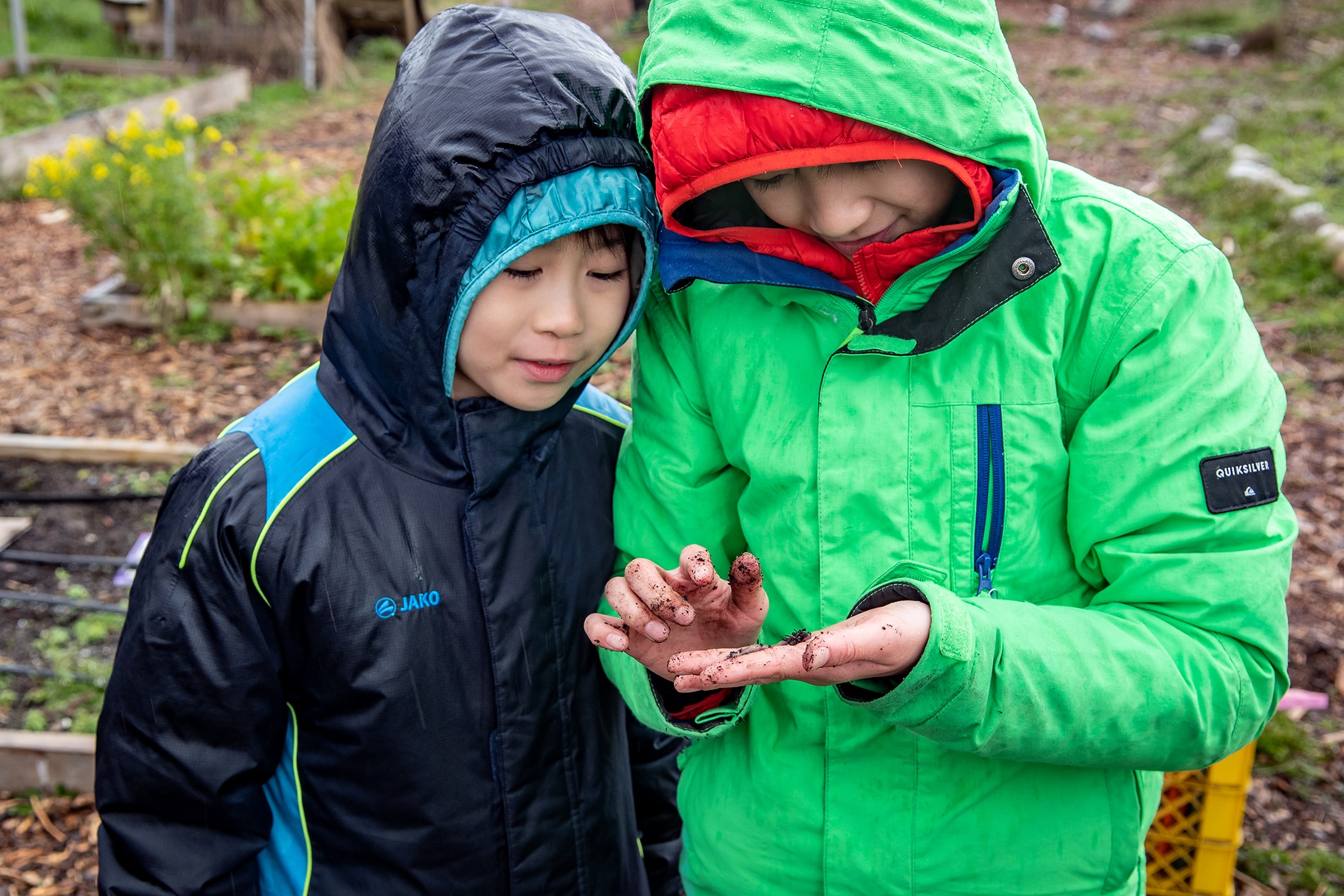 Two children take a close look at a worm.