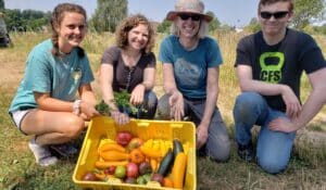 Volunteers show off their freshly picked harvest of tomatoes and squash on the 21 Acres farm.