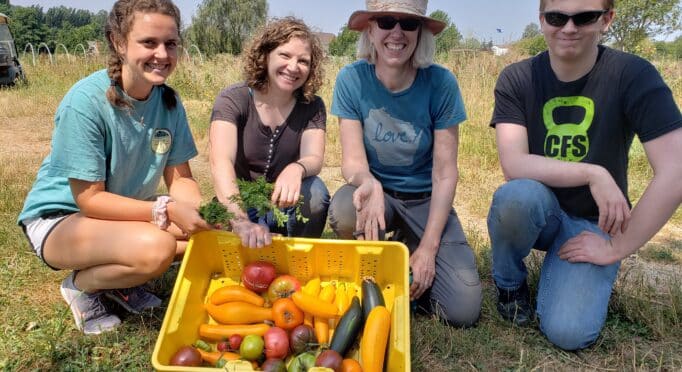 Volunteers show off their freshly picked harvest of tomatoes and squash on the 21 Acres farm.