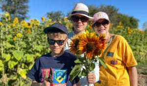 Sebastian, Katerina and Valentina show off the flowers they picked in the 21 Acres U-Pick sunflower field.