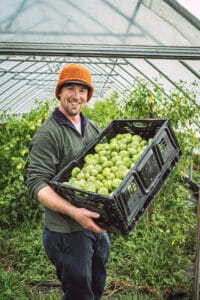 Sammamish Farms owner Erik Goheen holds a crate full of tomatillos in his greenhouse.