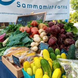 The Sammamish Farms booth full of fresh produce at a farmers market.