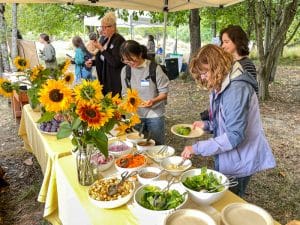 21 Acres volunteers load their plates with woodfired pizza and sides at the 2023 Volunteer Gratitude Garden Party.