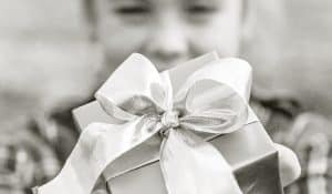 Photo of a girl holding a gift with a ribbon.