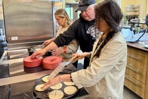 Chef Ron and two women cook fresh masa corn tortillas in the 21 Acres kitchen.